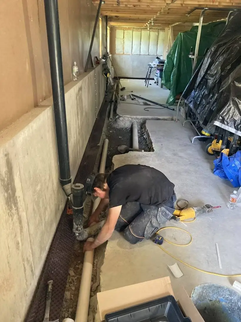 Technician installing interior basement drainage.